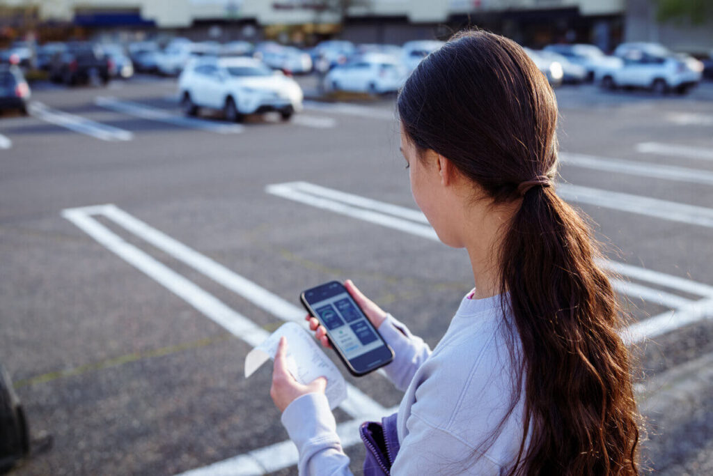 Mulher usando aplicativo de estacionamento no celular para pagamento digital em vaga de estacionamento